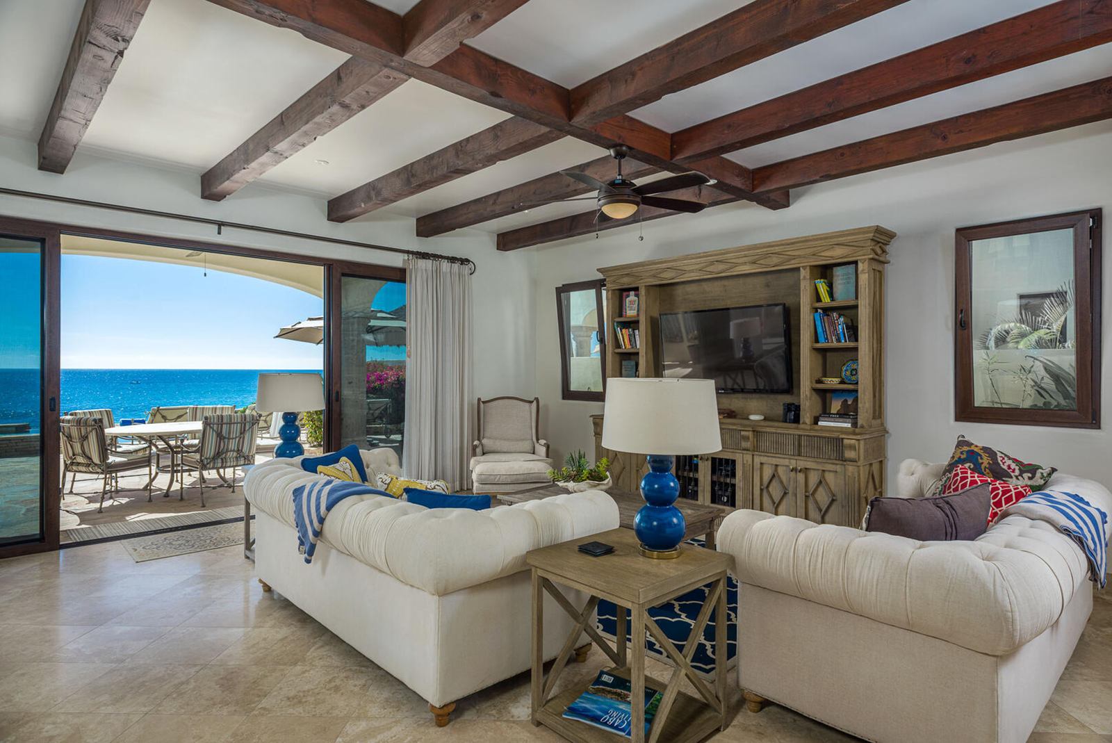 Living room with beamed ceiling and sliding doors open to the ocean at a San José del Cabo villa
