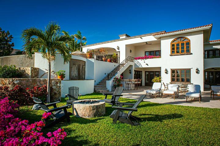 Lawn with fire pit, Adirondack chairs and bougainvillea behind a Palmilla villa